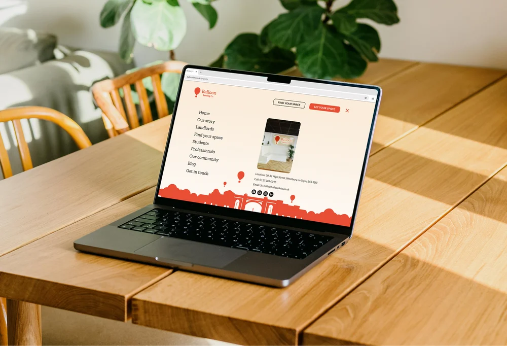 Balloon Lets website navigation menu shown on a MacBook on a wooden table