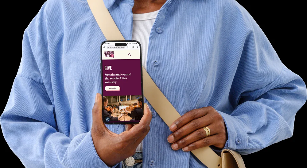 Langham Arts 'Give' donation page shown on an iPhone held by a person