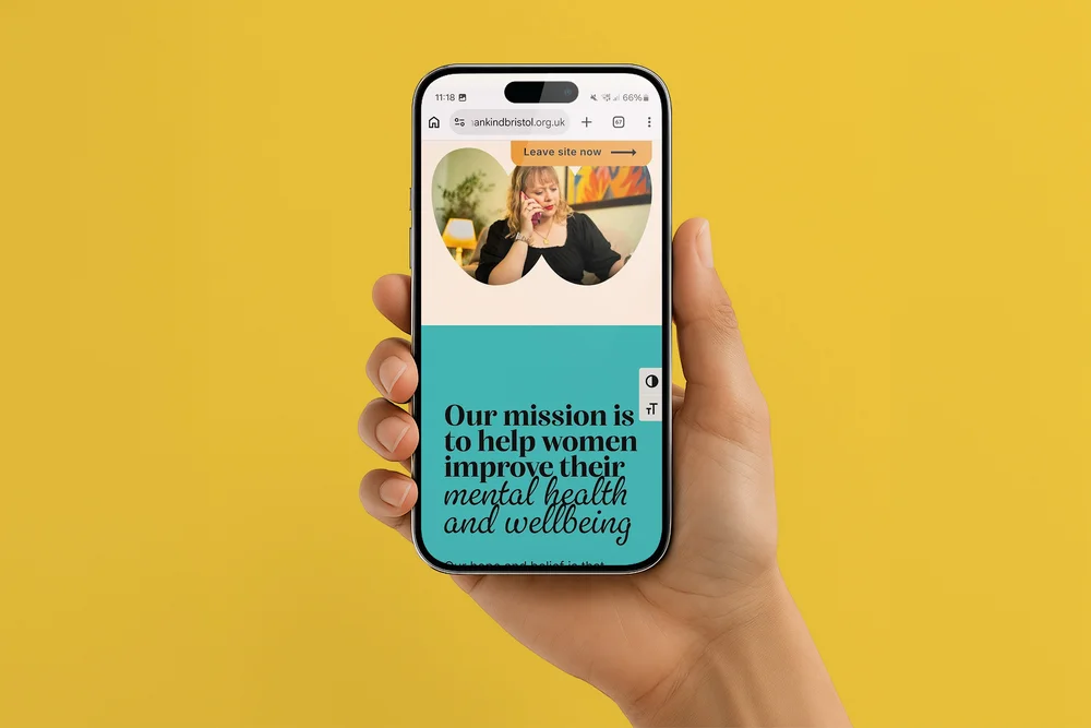Womankind Bristol mission statement shown on an iPhone held in hand against a yellow background